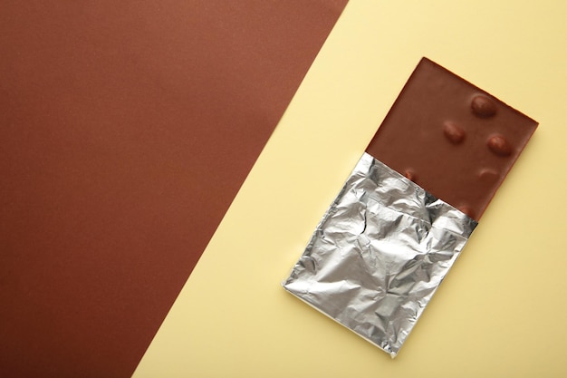Chocolate envolto em traçado de recorte de folha em fundo marrom