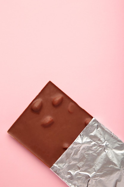 Chocolate envuelto en papel aluminio trazado de recorte sobre fondo púrpura Foto vertical