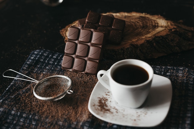 Chocolate escuro com miolo de café e nozes em uma mesa rústica