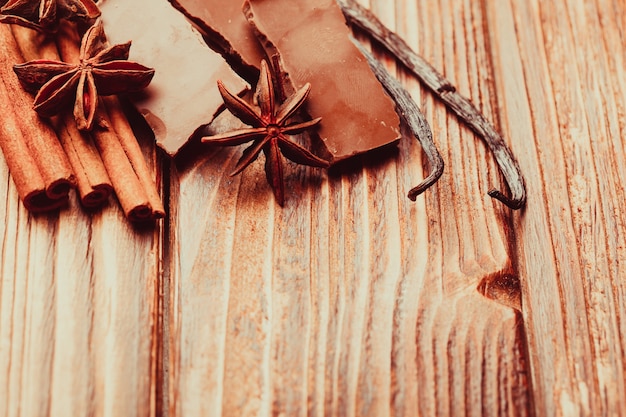 Foto chocolate con especias: anís, vainilla, canela en el fondo de madera