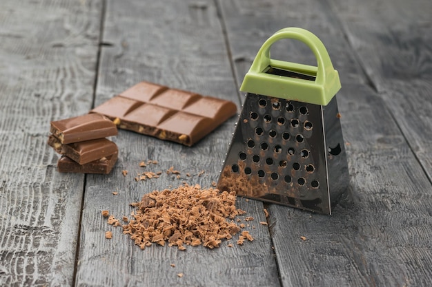 Chocolate con leche y un rallador de metal sobre una mesa de madera