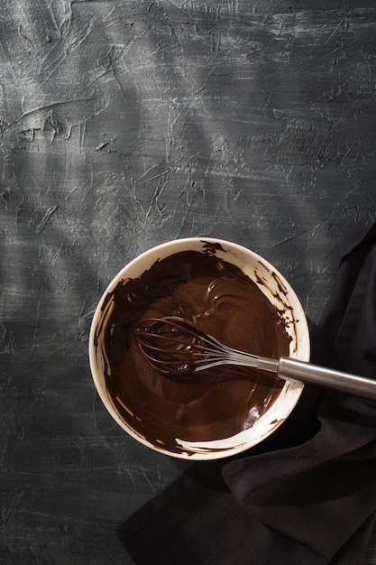 Chocolate líquido em um prato sobre a mesa O chef prepara ganache de chocolate em um fundo cinza