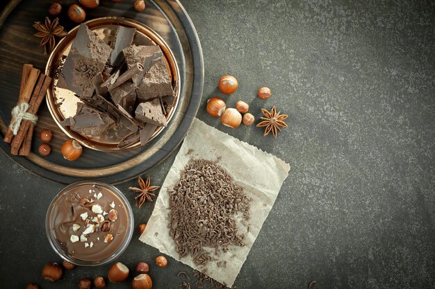 Foto chocolate negro en una composición con granos de cacao y nueces, sobre un fondo antiguo.