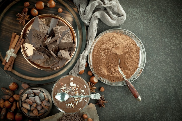 Chocolate negro en una composición con granos de cacao y nueces, sobre un fondo antiguo.