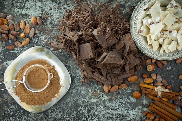 Chocolate negro en una composición con granos de cacao y nueces, sobre un fondo antiguo.