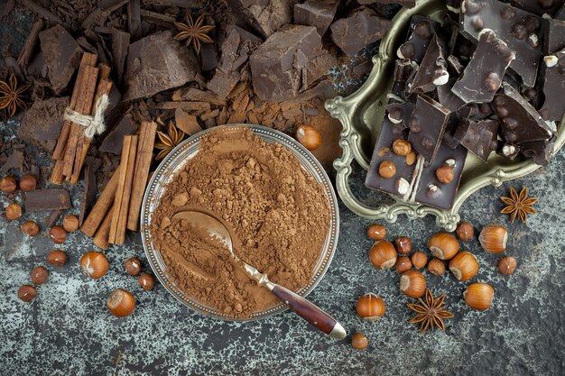 Chocolate negro en una composición con granos de cacao y nueces, sobre un fondo antiguo.