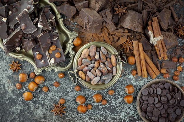 Chocolate negro en una composición con granos de cacao y nueces, sobre un fondo antiguo.