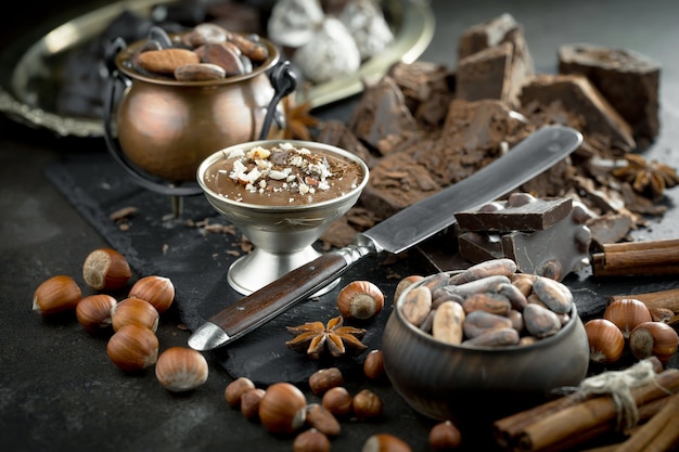 Chocolate negro en una composición con granos de cacao y nueces, sobre un fondo antiguo.