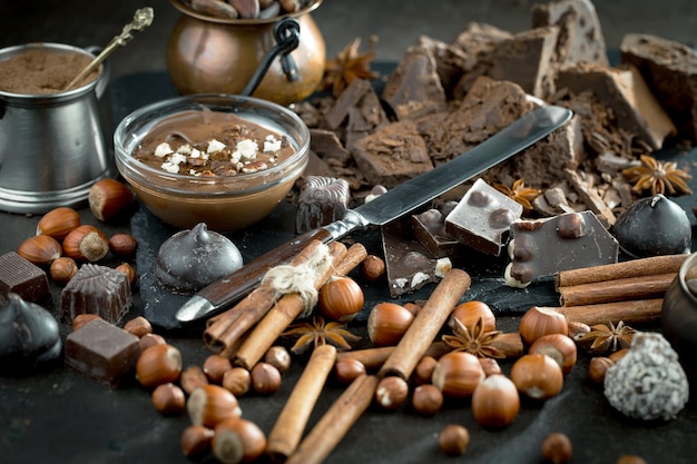 Chocolate negro en una composición con granos de cacao y nueces, sobre un fondo antiguo.