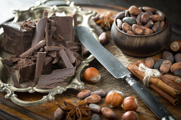 Chocolate negro en una composición con granos de cacao y nueces, sobre un fondo antiguo.