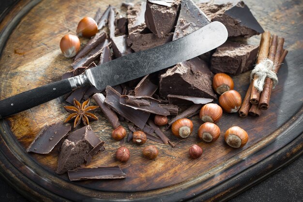 Chocolate negro en una composición con granos de cacao y nueces, sobre un fondo antiguo.