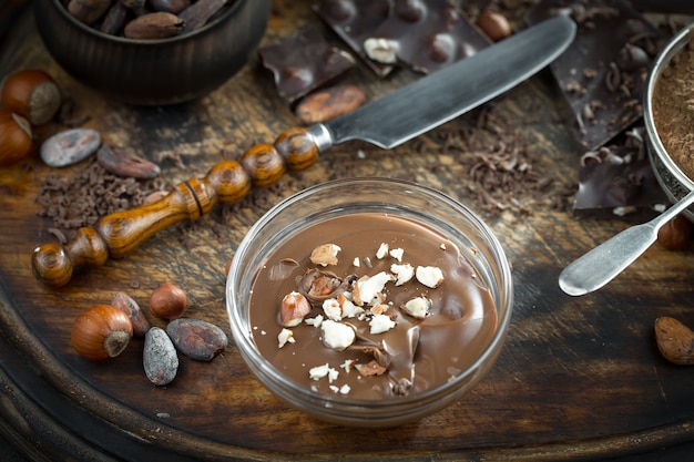 Chocolate negro en una composición con granos de cacao y nueces, sobre un fondo antiguo.