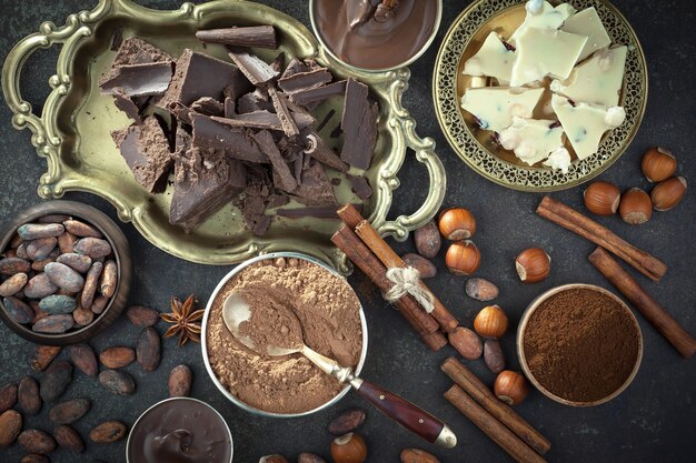 Chocolate negro en una composición con granos de cacao y nueces, sobre un fondo antiguo.