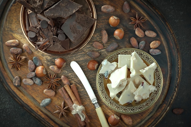 Chocolate negro en una composición con granos de cacao y nueces, sobre un fondo antiguo.