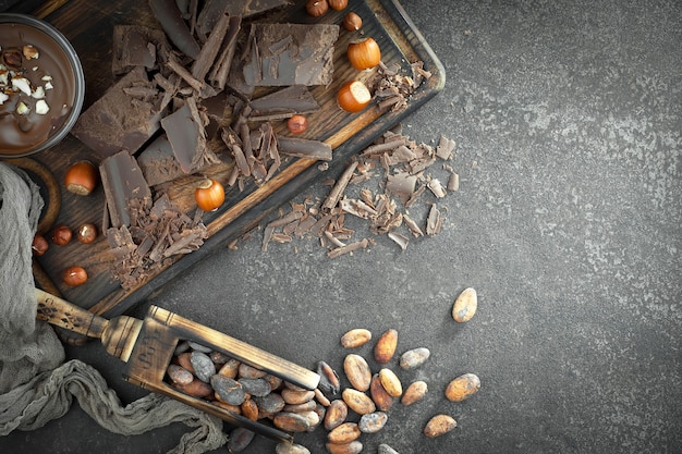 Chocolate negro en una composición con granos de cacao y nueces, sobre un fondo antiguo.