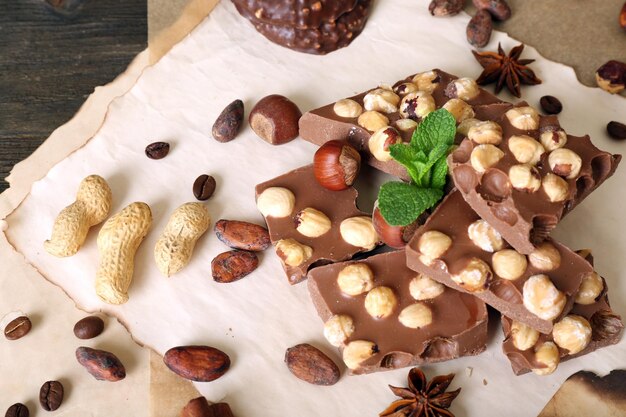 Foto chocolate con nueces, especias y menta en primer plano de papel