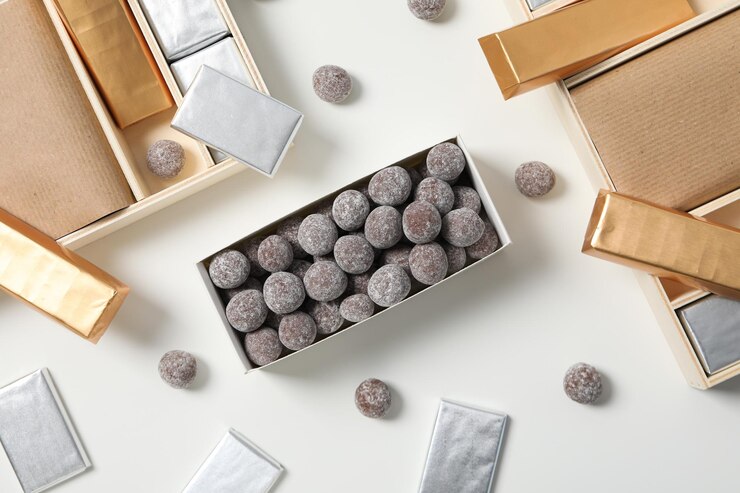 Chocolate en papel de aluminio y dulces en caja en la vista superior de fondo blanco