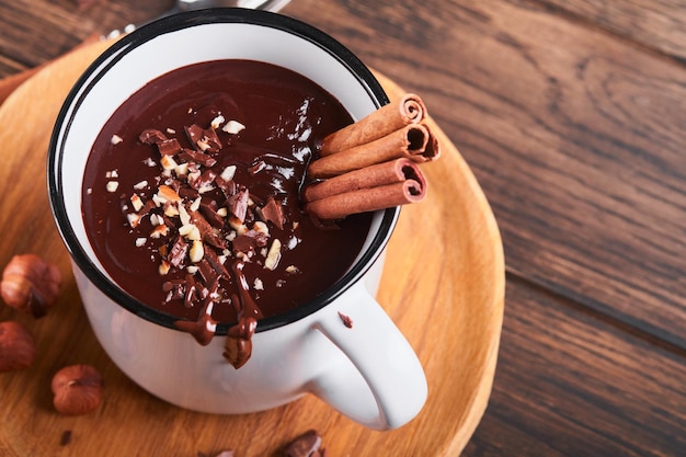 Chocolate quente chocolate quente picante caseiro com canela esmagada avelã em caneca de esmalte sobre fundo de madeira velho feriados sazonais aconchegantes