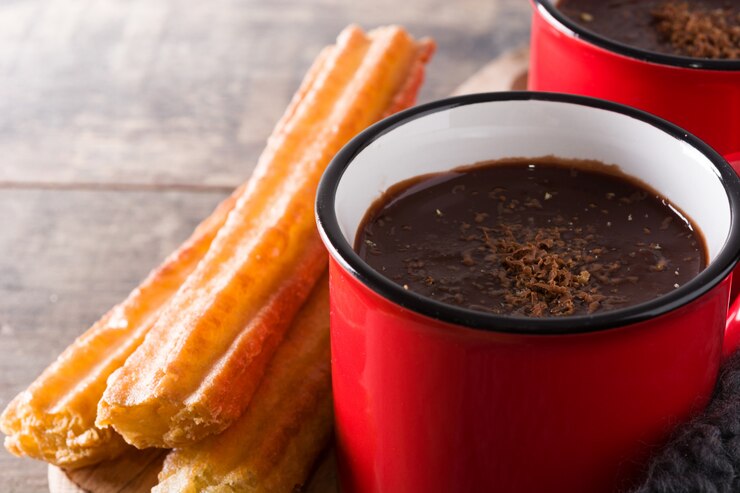 Foto chocolate quente com churros na mesa de madeira fechar