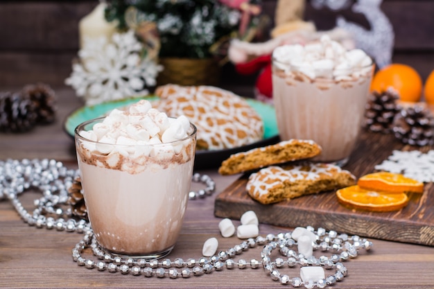 Chocolate quente com marshmallows e canela em copos na mesa em decorações de Natal