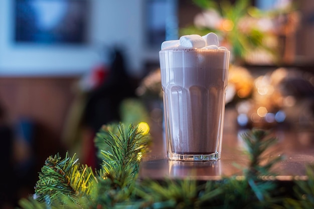 Chocolate quente com marshmallows em um vidro transparente em um café no fundo da decoração de ano novo.
