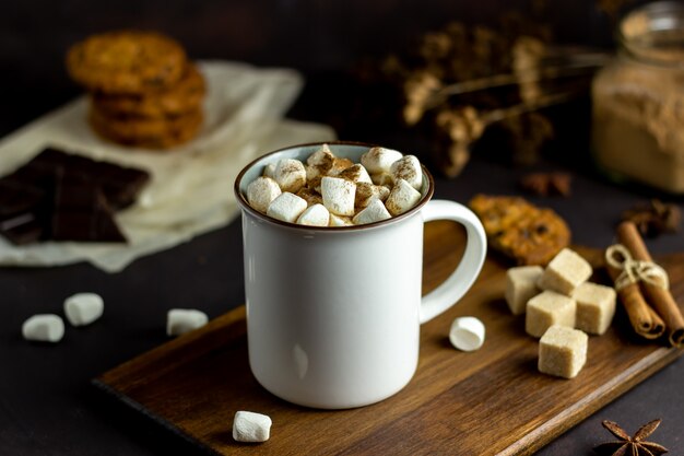 Chocolate quente com marshmallows em uma caneca branca em um enferrujado