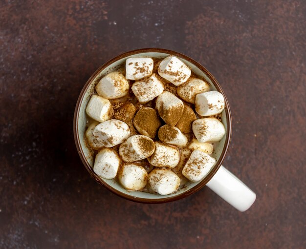 Chocolate quente com marshmallows em uma caneca branca em um enferrujado