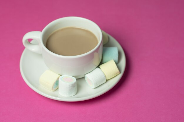 Chocolate quente com marshmallows em uma xícara de cerâmica no fundo de papel rosa