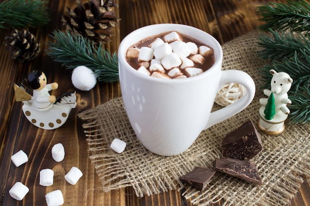 Chocolate quente com marshmallows no copo branco sobre o rústico