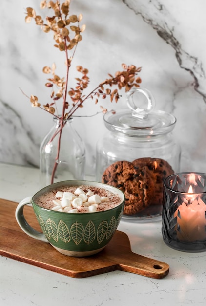 Chocolate quente com marshmallows, um pote de biscoitos, vela leve, interior aconchegante da cozinha