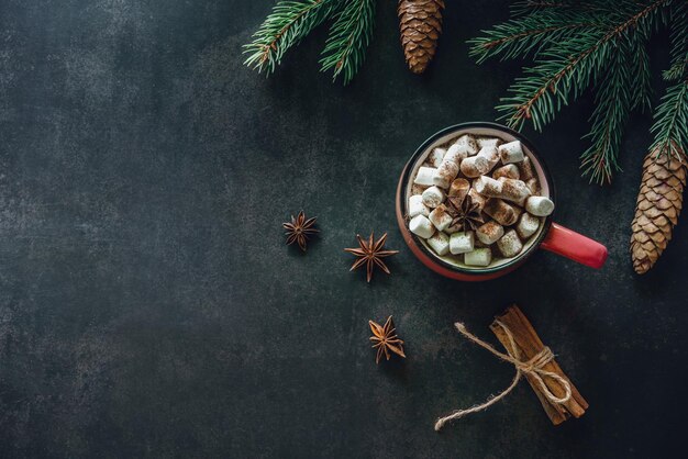 Chocolate quente de marshmallow e galhos de árvore de Natal em fundo escuro