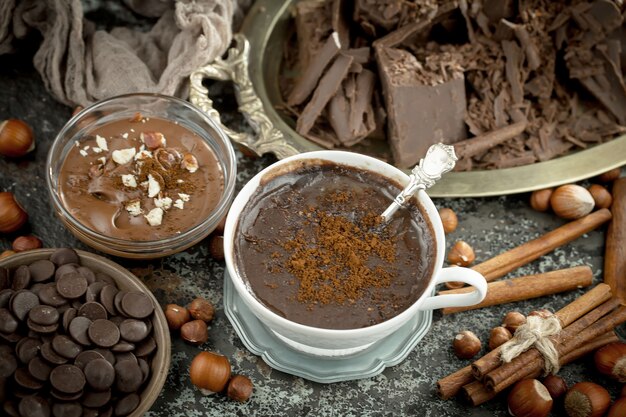 Foto chocolate quente em um fundo antigo em uma composição com grãos de cacau e nozes.