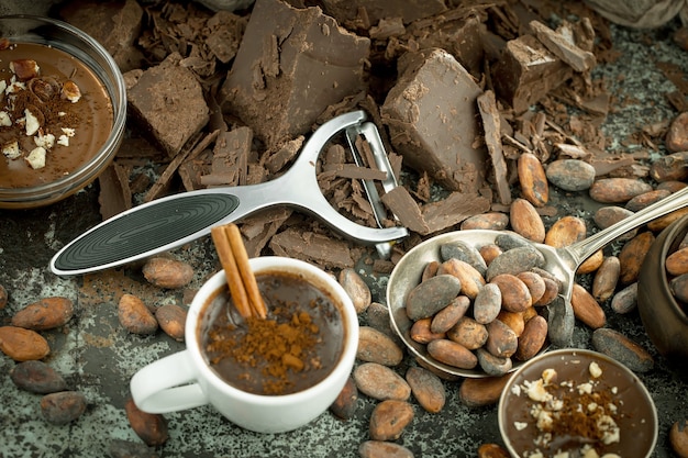 Foto chocolate quente em um fundo antigo em uma composição com grãos de cacau e nozes.