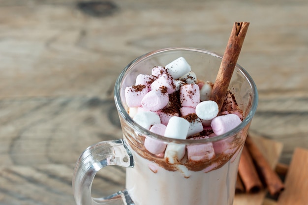 Chocolate quente ou bebida de chocolate com marshmallow em caneca de vidro na mesa de madeira. Conceito de aconchegantes feriados de Natal e Ano Novo, copie o espaço.