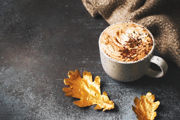 Chocolate quente ou xícara de café com espuma e folha dourada em fundo escuro