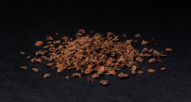 Foto chocolate ralado. pilha de chocolate moído isolado em preto, closeup