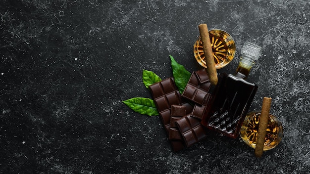 Chocolate uísque e charutos em uma mesa de pedra preta Vista superior Espaço livre para o seu texto