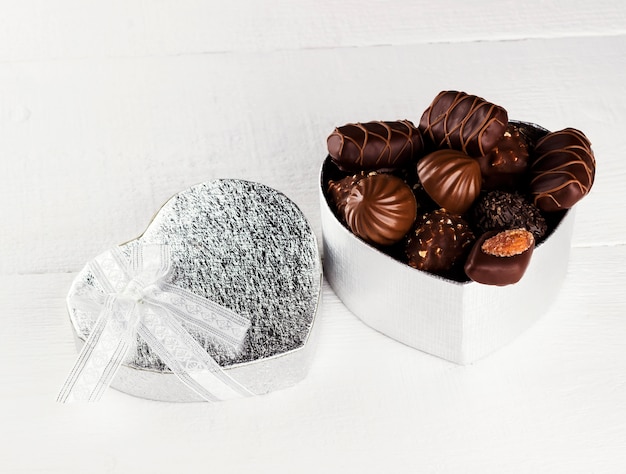 Chocolates en una caja en forma de corazón sobre un fondo blanco.