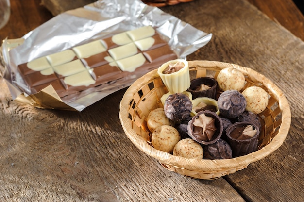 Chocolates y chocolate en una cesta en una mesa de madera