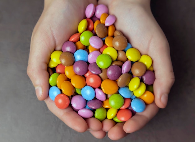 Chocolates de diferentes colores en las palmas de los niños delicias infantiles vista superior