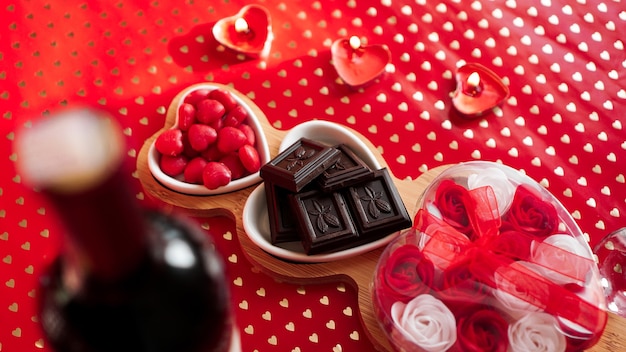 Chocolates e doces em pratos em forma de coração. Configuração de mesa festiva para data de namorados. Fundo vermelho