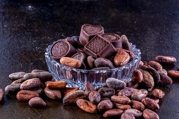 Chocolates em bandeja de vidro esculpida, fotografados em um fundo escuro.