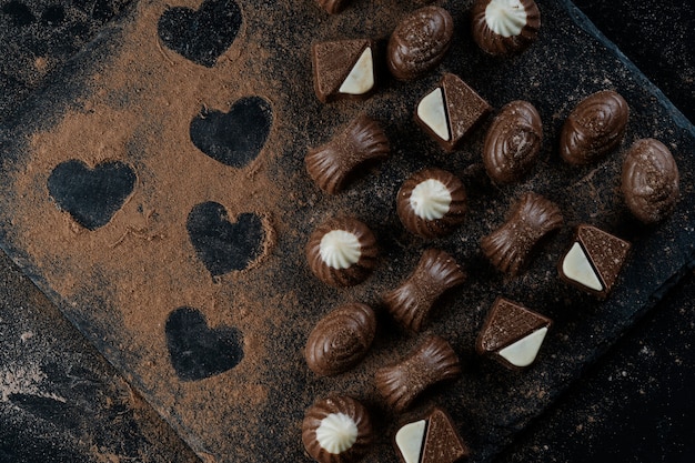 Chocolates em pedra negra com cacau em pó formando corações