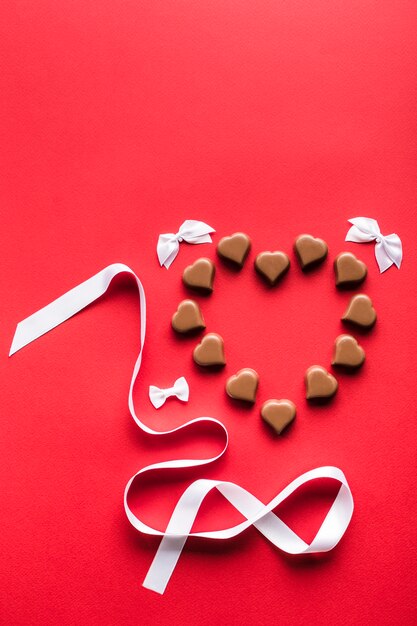 Chocolates en forma de corazón sobre fondo rojo para el día de San Valentín