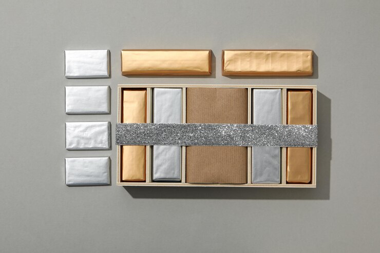Chocolates en papel de aluminio y en caja con cinta en la vista superior de fondo gris