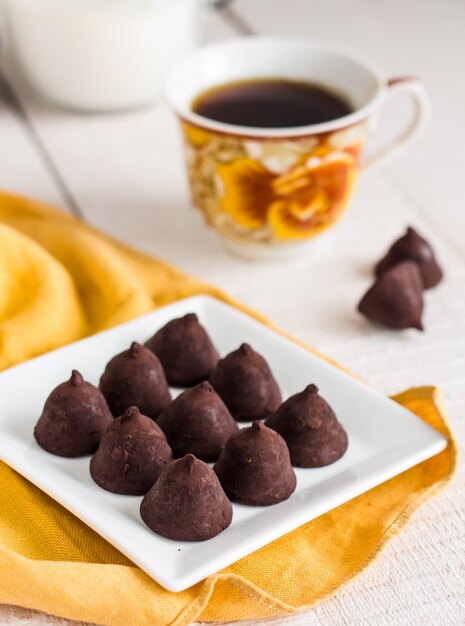 Chocolates trufados com uma xícara de café e creme em um branco