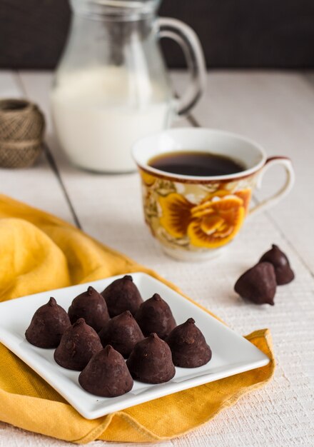 Chocolates trufados com uma xícara de café e creme em um branco