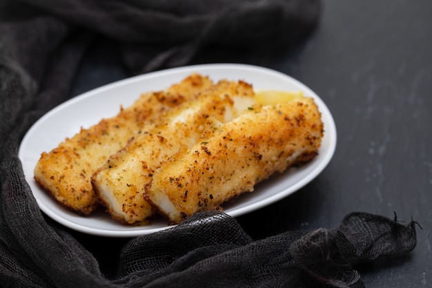 Chocos de tiras fritas no prato branco sobre preto