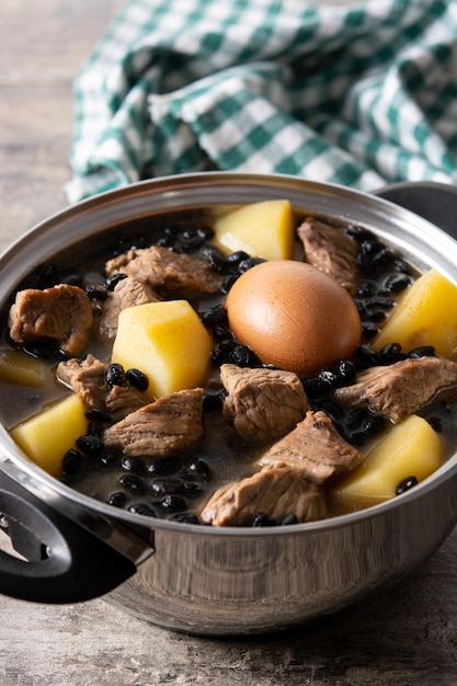 Cholent judaico tradicional em caçarola na mesa de madeira