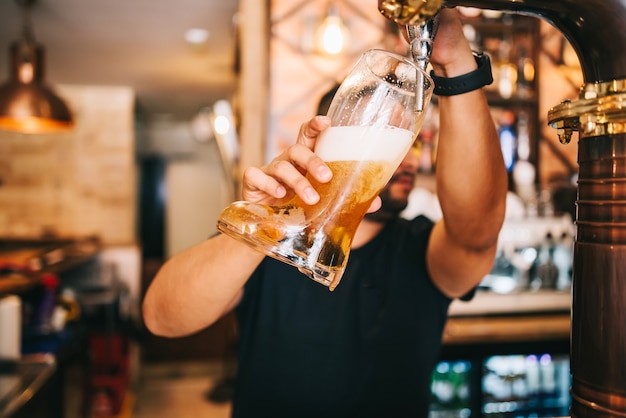 Foto chope do barman na torneira na bota de vidro de cerveja.